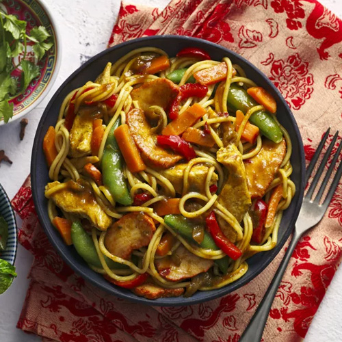 Slimming World food range Singapore-style noodles in a grey bowl on a red tablecloth and white table.