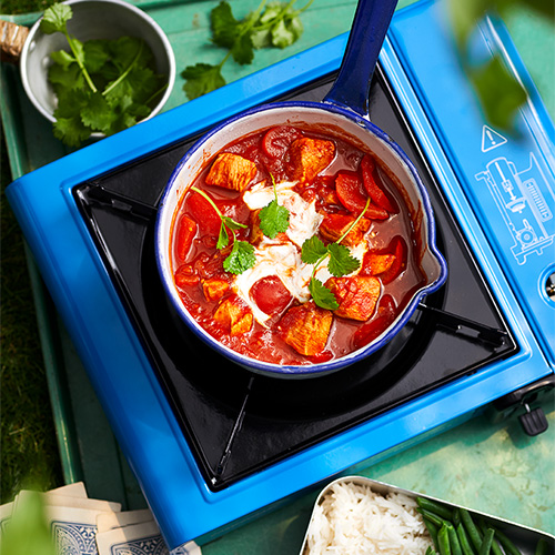 Slimming World chicken tikka masala. The masala is being cooked in a dark blue saucepan on top of a blue camping stove.