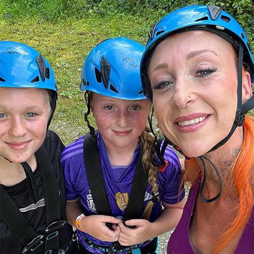 Slimming World member Nicola and her two children. All three are wearing a blue climbing helmet and black harness.